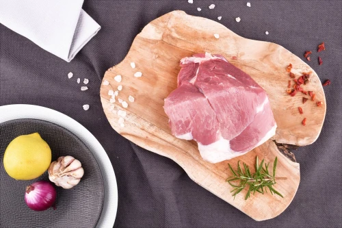 Surowa łopatka wieprzowa EKO 500g na drewnianej desce z przyprawami i cytryną