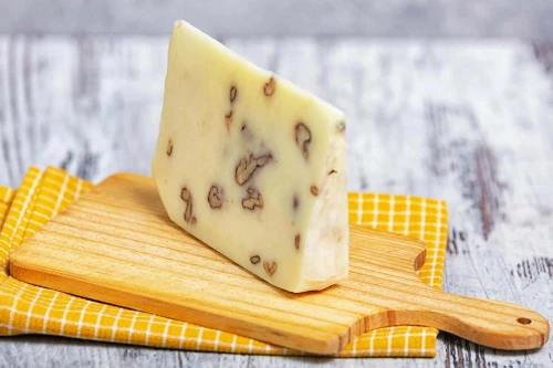 Pecorino Primosale z dodatkiem pistacji – włoski ser owczy na desce z pistacjami i pieczywem